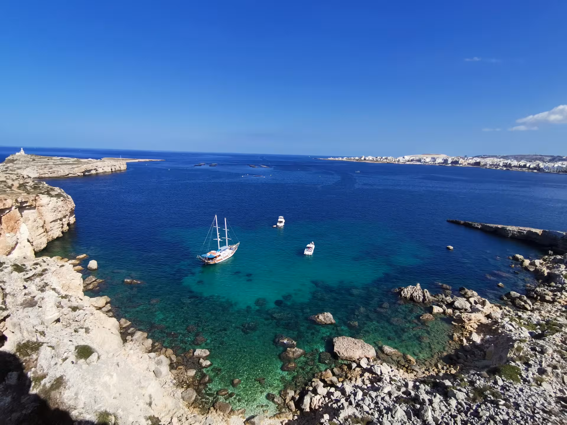 Panoramic Saint Pauls Bay Malta hike view with boats in a turquoise cove, part of the guided walk and local picnic