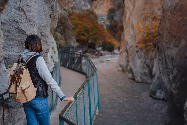 Adventurer with backpack explores the narrow walkway in Saklıkent Canyon, admiring the autumnal landscape.