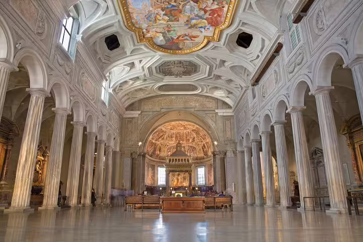 Interior of San Clemente Basilica in Rome with ornate frescoed ceiling and nave visited on an underground no-line private tour