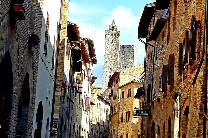 Medieval stone towers and narrow cobbled street in San Gimignano, a highlight of private shore excursion from Livorno