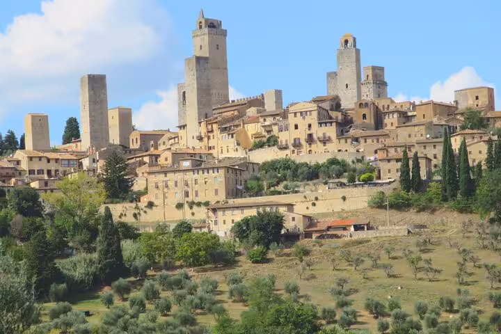 Scenic view of San Gimignano's medieval towers surrounded by lush Tuscan countryside.