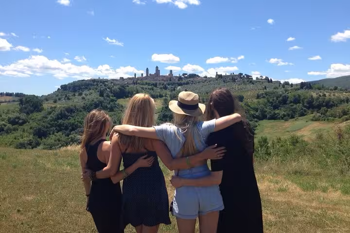 Group of friends enjoying the scenic view of San Gimignano's rolling hills during a Tuscany wine tour.