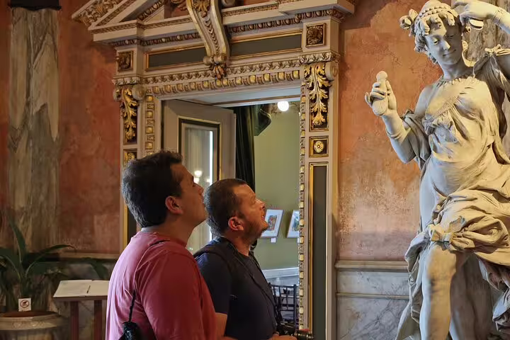 Visitors admire a detailed statue in a historic building, part of the San Jose By Night cultural tour experience.