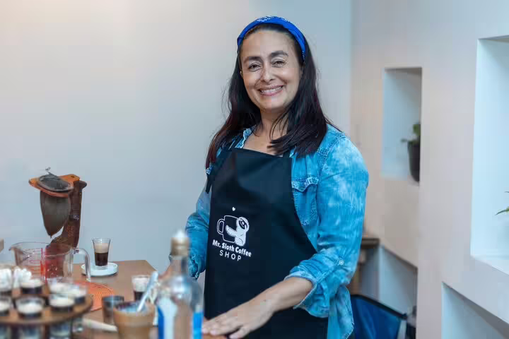 Smiling woman in apron prepares for farm-to-table dinner in San Jose night tour, showcasing local culinary traditions.