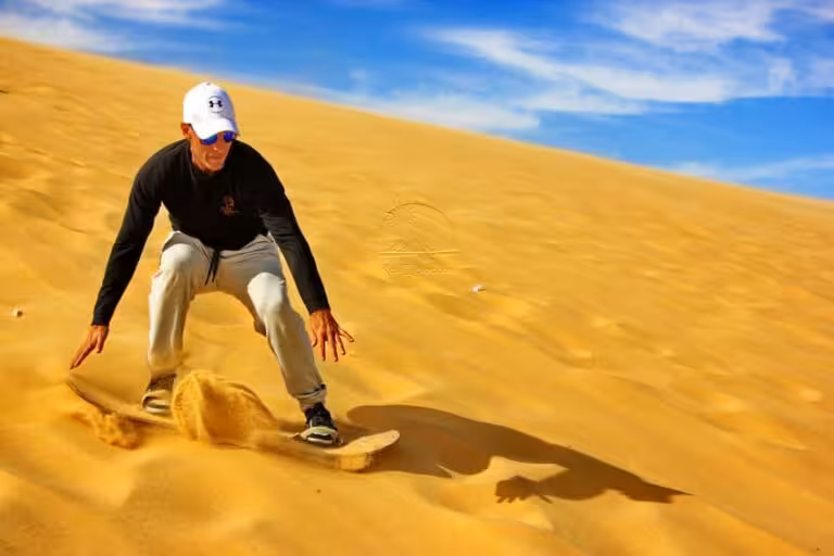Sandboarding on golden dunes in Fayoum Oasis desert, thrilling 2-day Cairo to Fayoum adventure tour