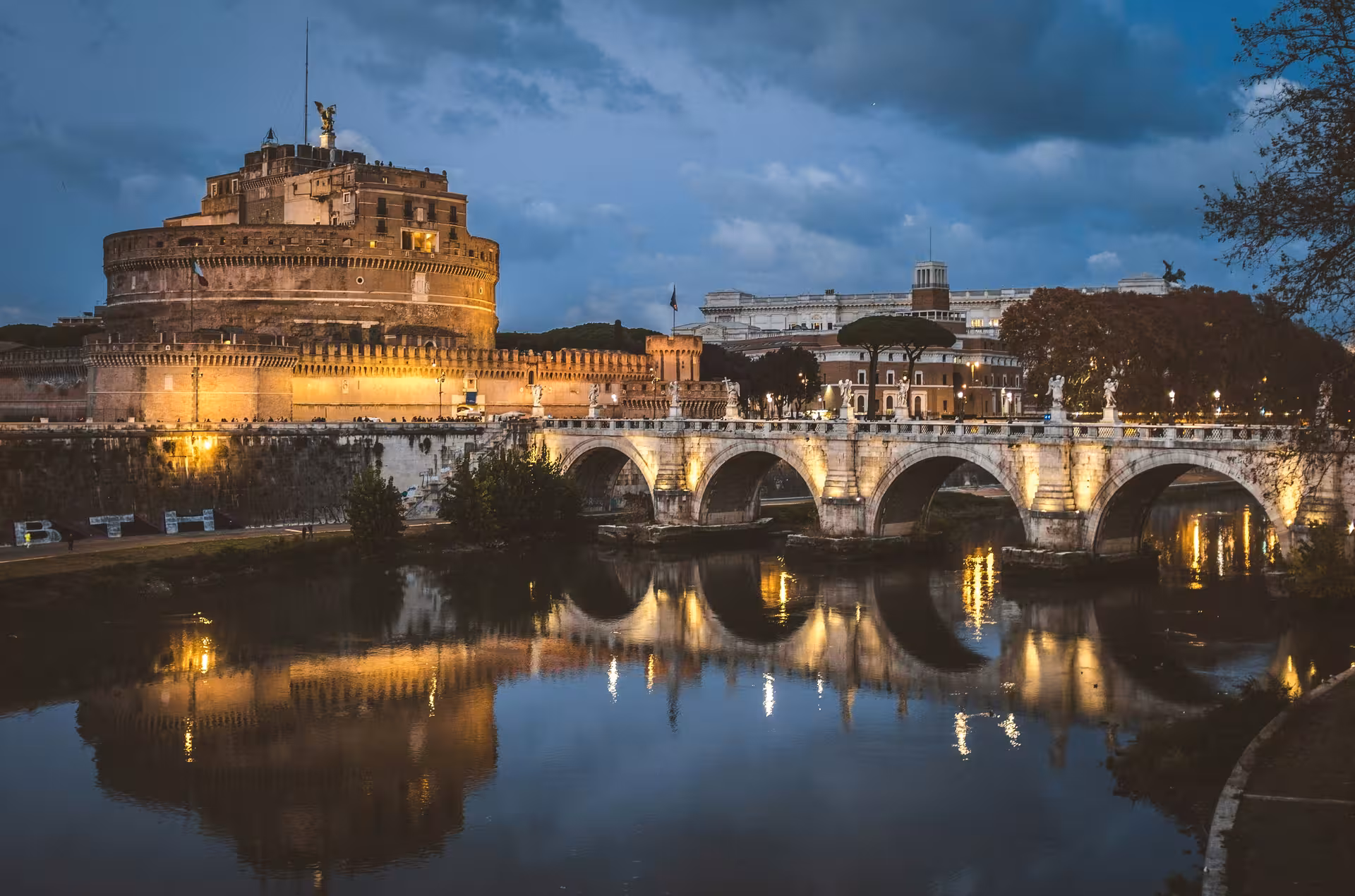 Evening view of Sant'Angelo Castle illuminated along the Tiber River with reflections, perfect for a Rome combo tour.