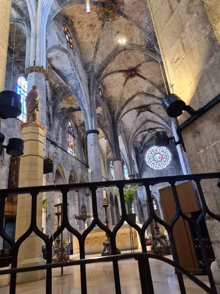 Interior of Santa Maria del Mar in Barcelona, featuring Gothic arches, stained glass windows, and intricate stonework.