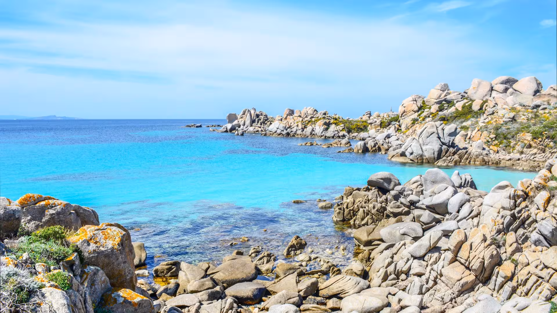 Scenic view of southern Corsica's rocky coastline with clear turquoise waters on a sunny day.