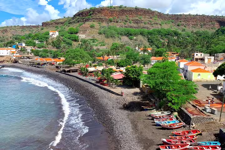 Coastal view near Cidade Velha, Santiago Island, with black-sand beach and fishing boats on guided tour from Calabaceira Valley