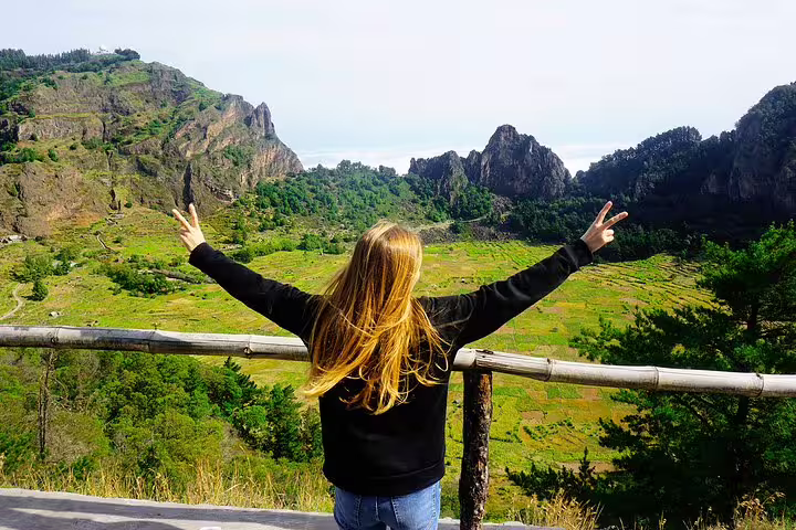 Traveler with open arms enjoys panoramic view of Santo Antão's lush green valleys and rugged mountains.