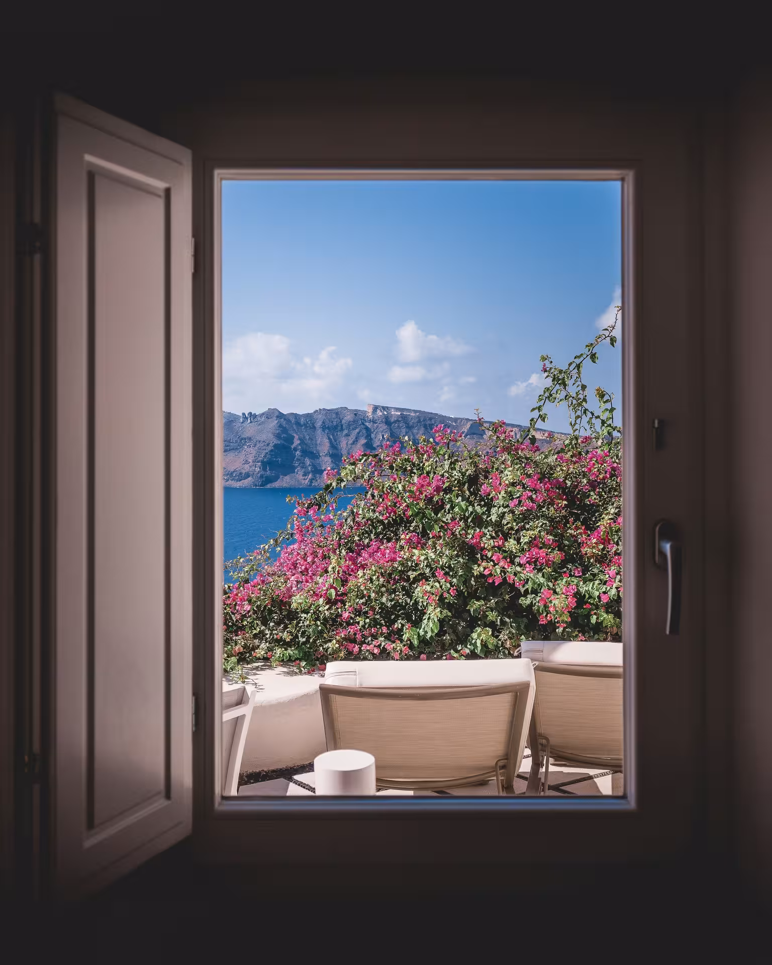 Caldera sea view from a Santorini terrace window with bougainvillea, ideal stop on Shore to Oia cruise tour