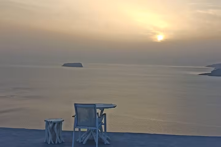 Santorini caldera sunset from terrace with chair and table overlooking the Aegean, Iconic Highlights Tour