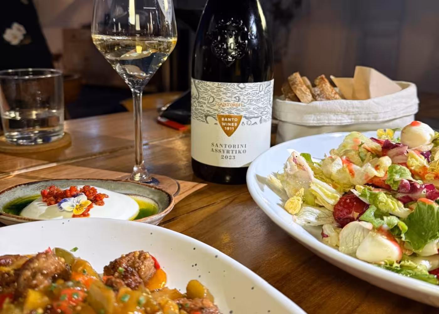 Santorini dinner at Santo Winery with Assyrtiko wine, Greek salad, and mezze on a rustic table
