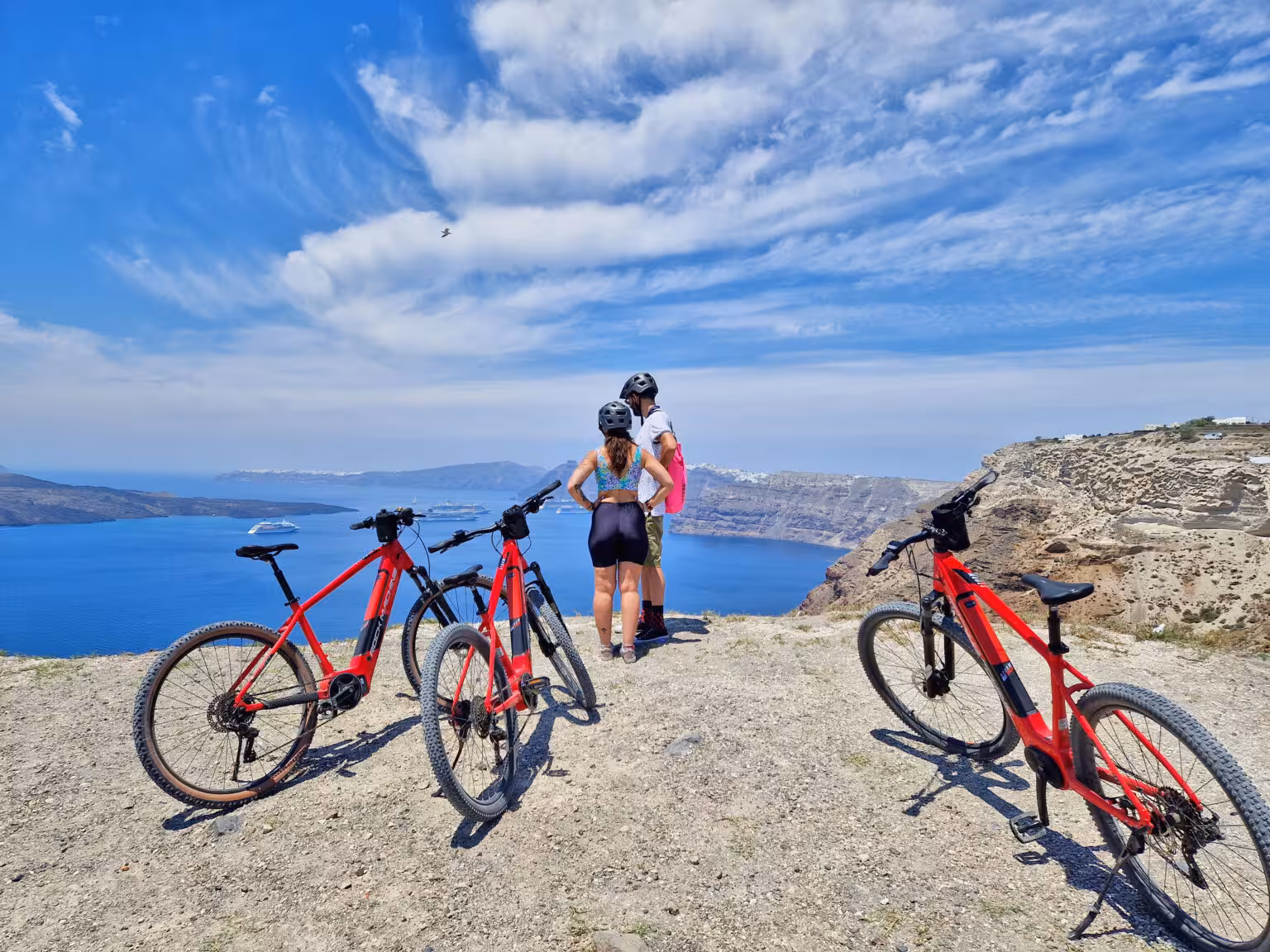 Riders with red e-bikes at Santorini caldera viewpoint on a guided morning e-bike tour with sea views