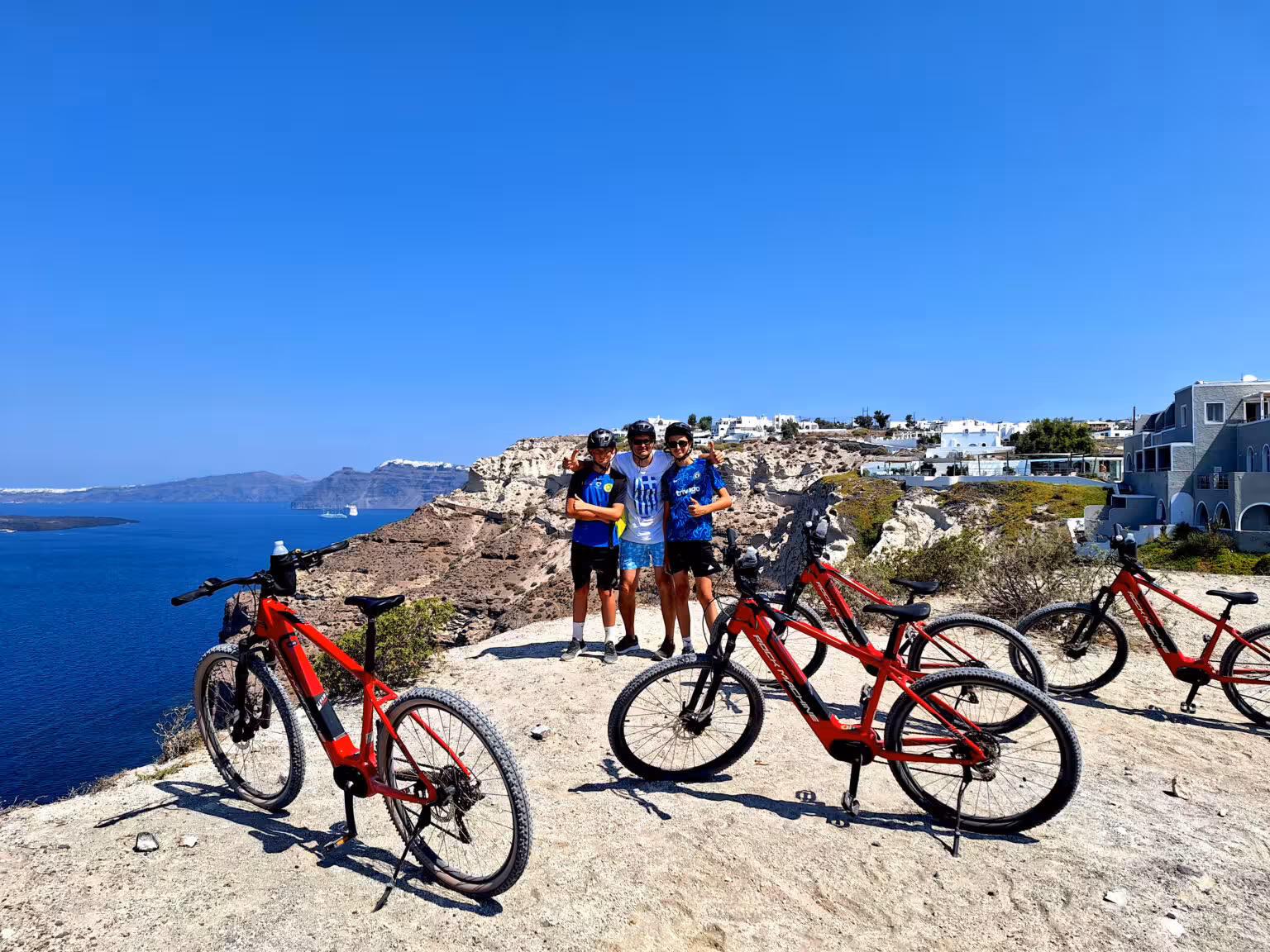 Group photo at Santorini caldera viewpoint with red e-bikes on a guided morning or sunset e-bike tour