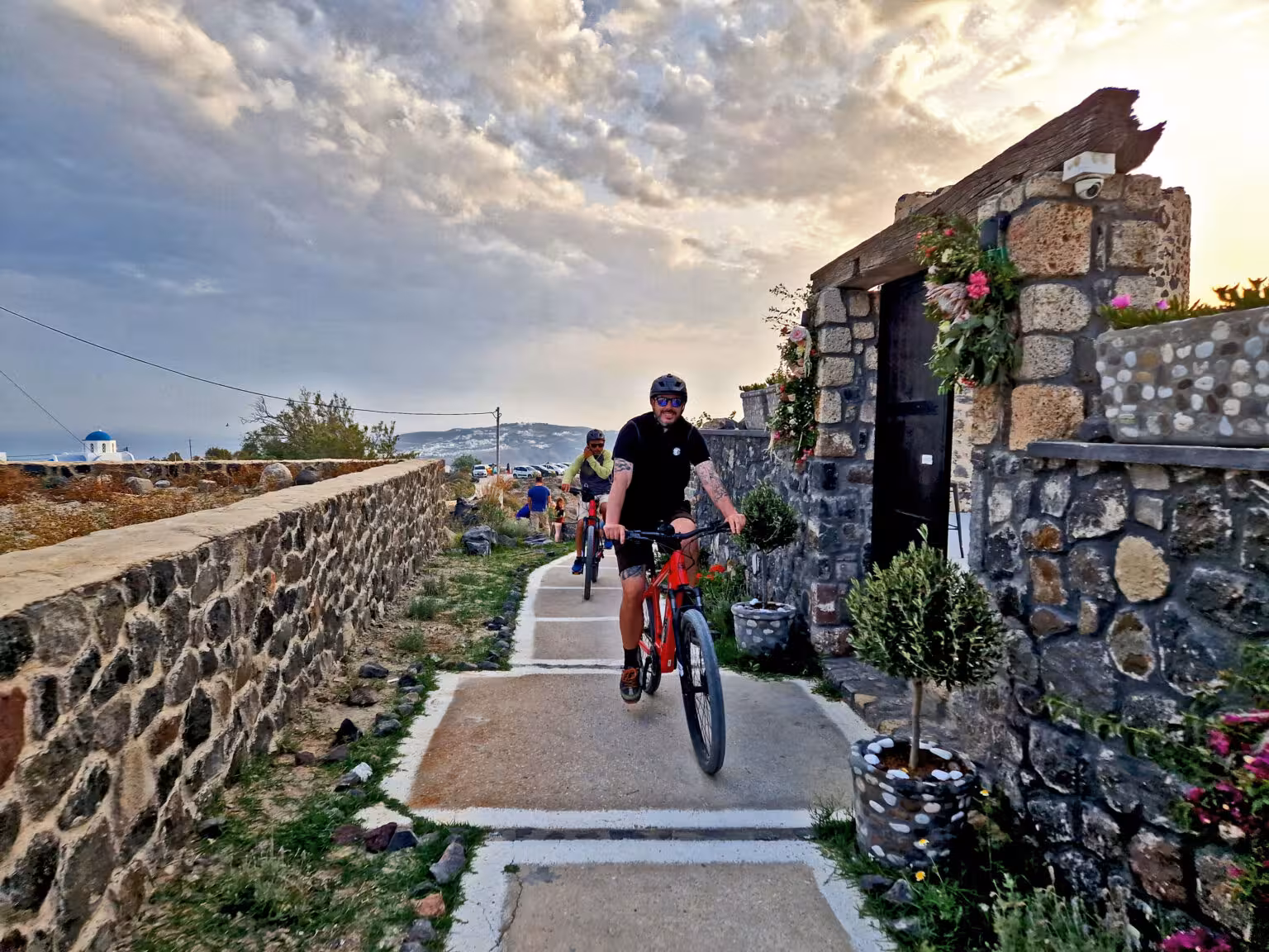 Guided Santorini e-bike tour riding past stone walls and village lane, ideal for morning or sunset ride
