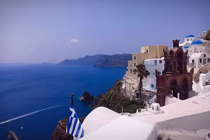 Santorini Fira caldera panorama with Greek flag and blue domes, private 3-day tour with transfer included