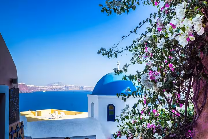 Santorini Oia blue-domed church and bougainvillea overlooking the caldera on a 7-day Athens Mykonos tour