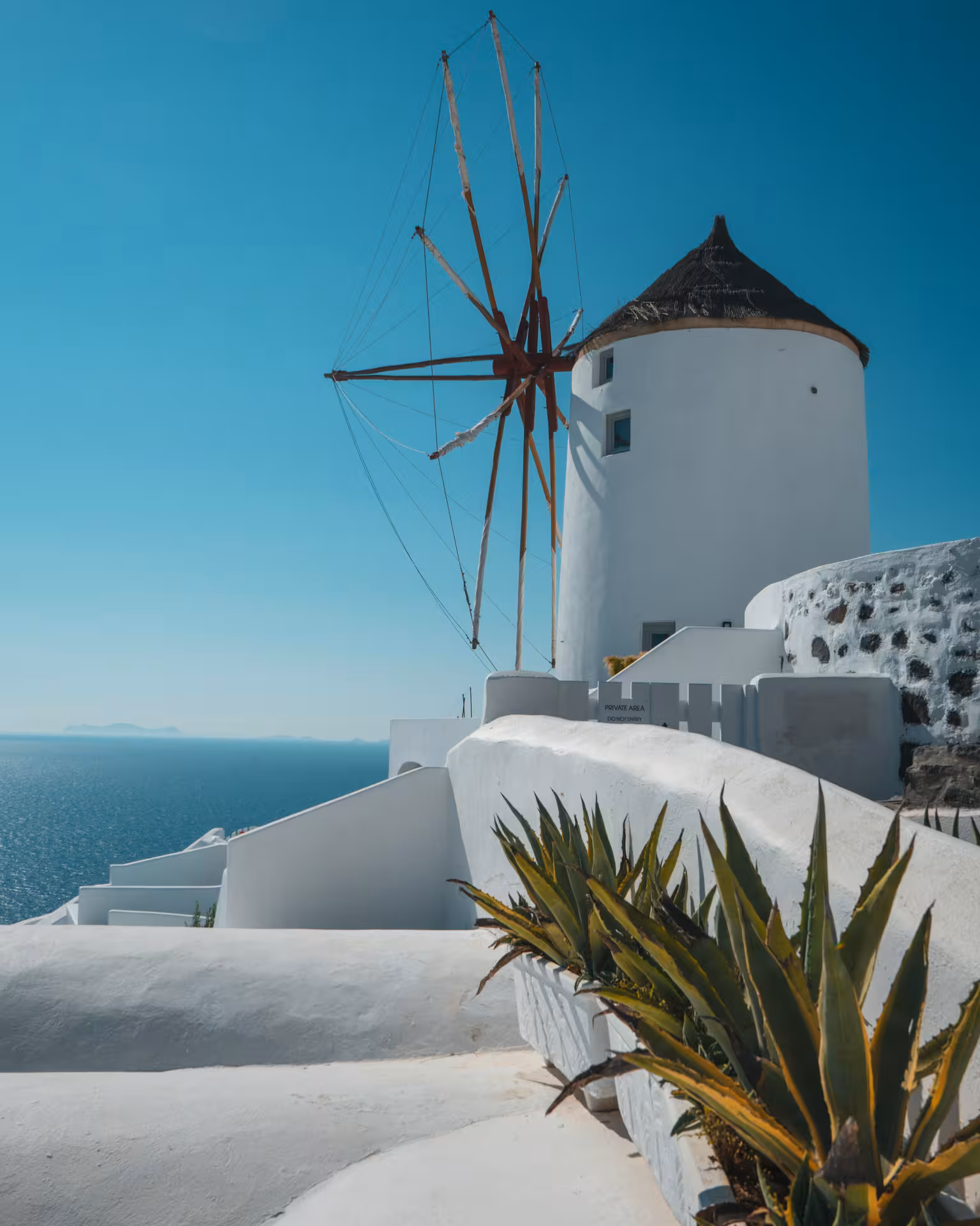 Traditional Oia windmill above whitewashed terraces and Aegean Sea, scenic stop on Santorini cruise excursion