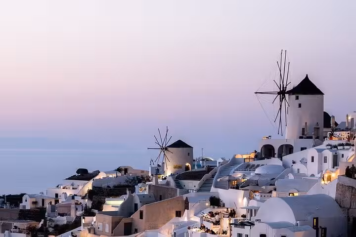 Oia windmills and whitewashed houses at sunset in Santorini, iconic stop on a private SUV tour to hidden gems