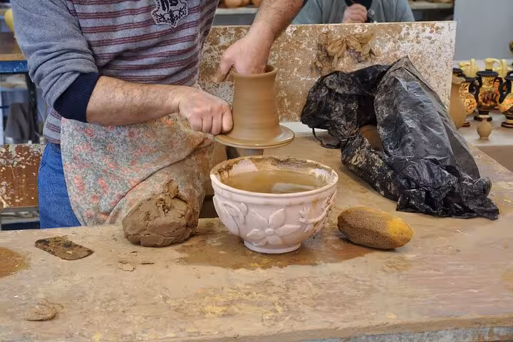 Hands shaping clay on a pottery wheel in Santorini, a tactile 5-senses workshop with local artisan