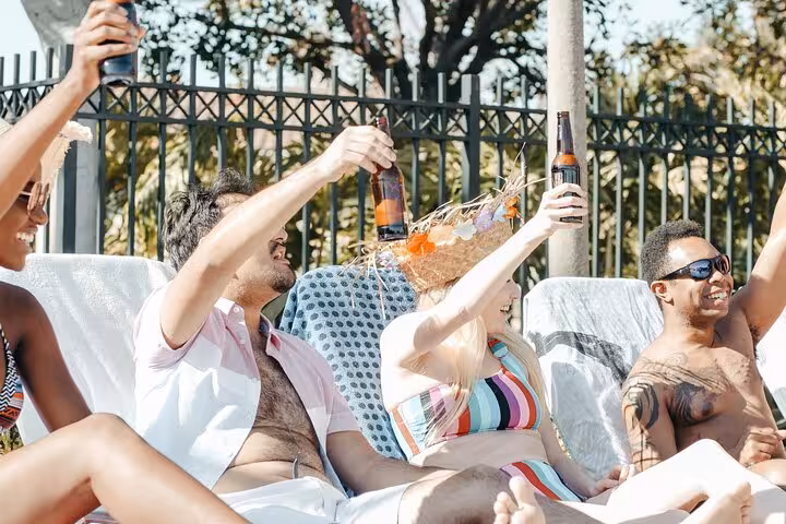 Friends toast by a private pool in Santorini, relaxing on loungers with sunny caldera day vibes