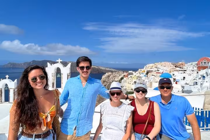 Guests on a tailored Santorini private tour posing by Oia churches with caldera views and iconic white houses