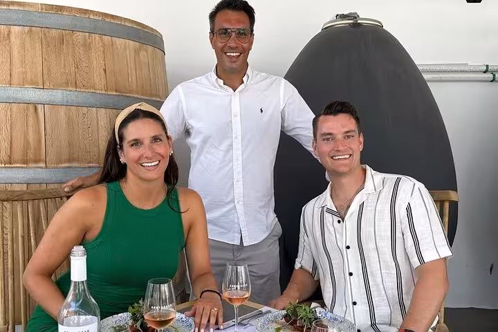Couple enjoying Santorini winery lunch and rosé tasting with host beside oak barrel on private wine tour