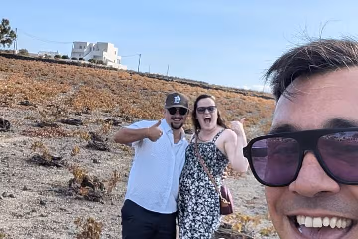 Friends posing in a Santorini vineyard on a private wine tasting tour with winery visits and lunch included
