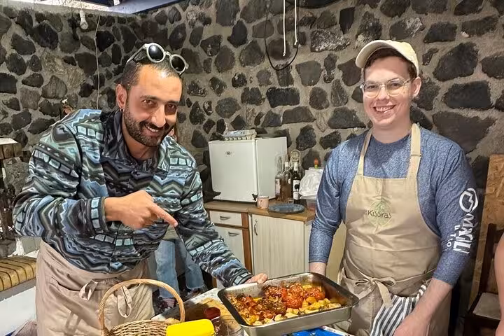 Guests cooking traditional Santorini lunch in a village kitchen during authentic farm-to-table tour