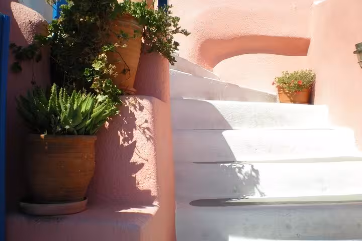 Sunlit white steps and terracotta pots in a quiet Santorini alley, a hidden gem stop on private SUV tour