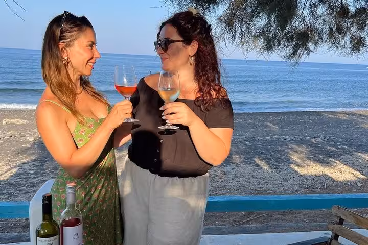 Friends toasting with Santorini wines on a private tasting tour, seaside stop between wineries and lunch