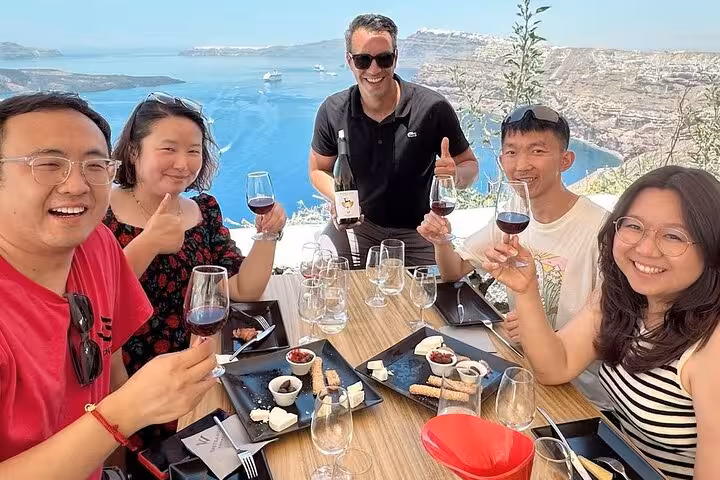 Friends enjoy red wine tasting with caldera views on a Santorini private wine tour visiting up to 4 wineries
