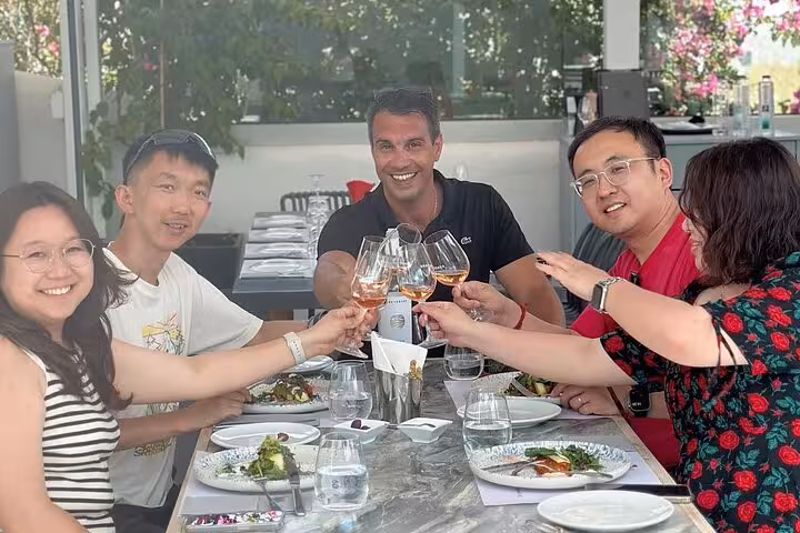 Group toasting with wine at winery lunch on Santorini private wine tasting tour visiting up to 4 wineries