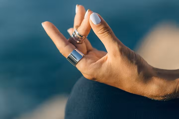 Close-up of meditating hand mudra during Santorini caldera yoga session with Aegean sea backdrop