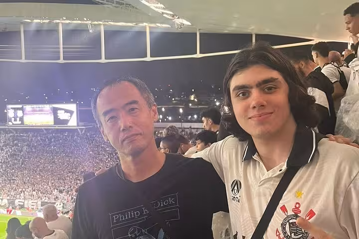 Fans pose in the stands at a São Paulo night match, after a local soccer game meetup with locals and travelers