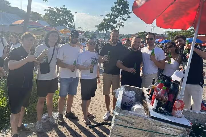 Travelers with local host enjoying pre-game drinks at a street stand before joining a São Paulo soccer match
