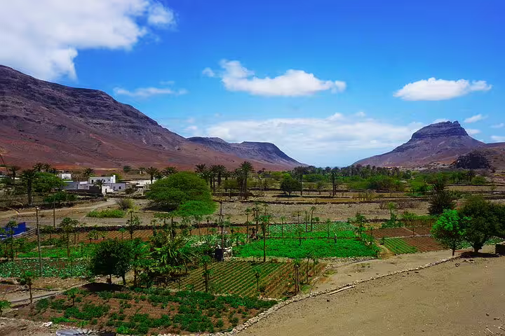 Lush green farmland nestled between mountains under a clear blue sky in São Vicente, Cape Verde, ideal for explorers.