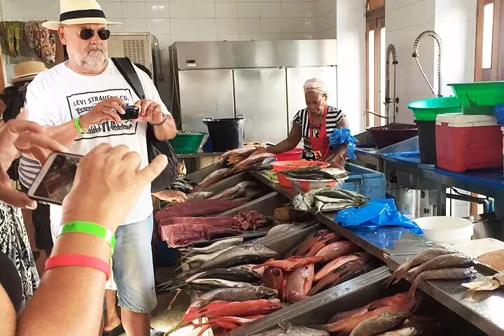 Visitors exploring vibrant São Vicente fish market with fresh seafood displayed on a guided cultural tour.