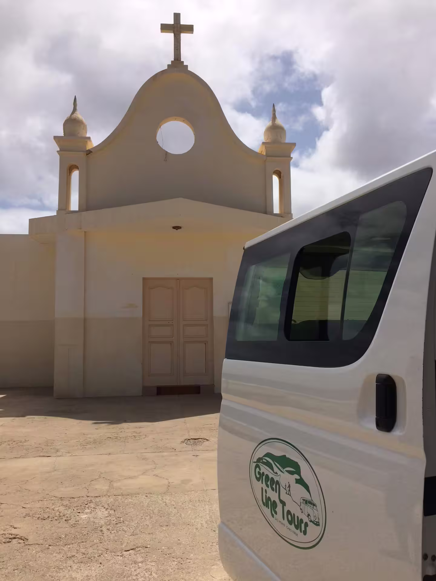 Tour van parked near a historic church under a bright sky in São Vicente, highlighting the island's cultural heritage and scenic tours.