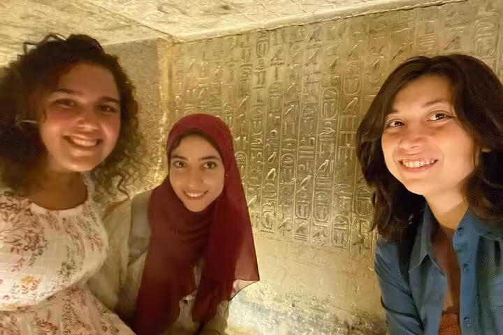 Visitors selfie inside Saqqara tomb with ancient hieroglyphs on Memphis and Dahshur pyramids day trip from Cairo