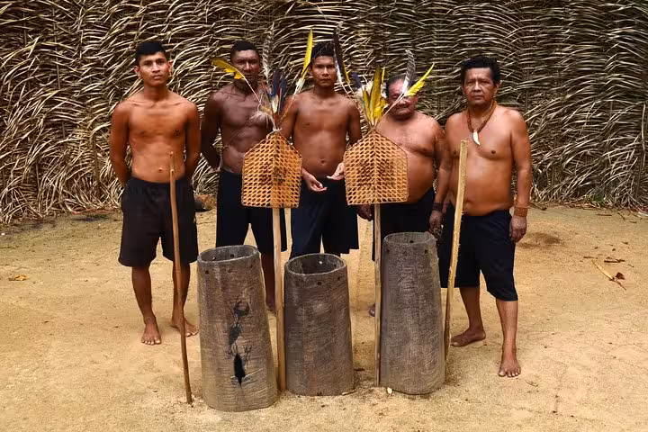 Indigenous men pose with Tucandeira ant gloves and ritual tools for Amazon rainforest cultural experience