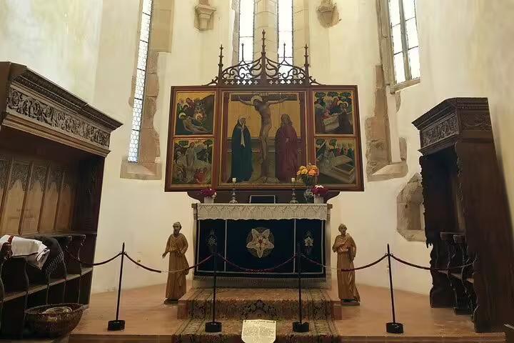 Medieval altar with crucifixion triptych painting and wooden statues inside a Saxon fortified church in Brasov