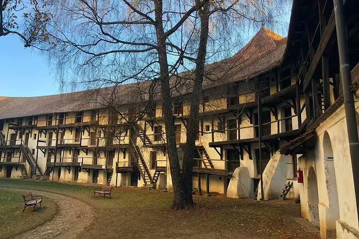 Courtyard of a Saxon fortified building with timber-framed galleries, wooden staircases, and bare trees in Brasov