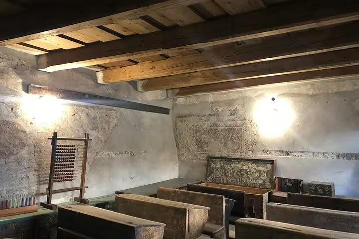 Historic classroom interior with wooden benches, abacus, and stone walls inside a Saxon fortification in Brasov