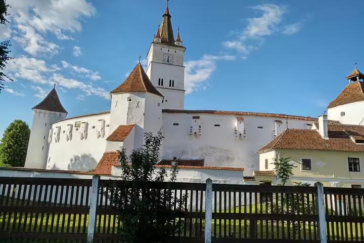 White fortified Saxon church with clock tower and terracotta roofs in Transylvania, Romania
