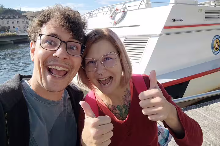 Smiling couple at Schaffhausen riverside dock near a boat on a self-guided scavenger hunt and sights tour