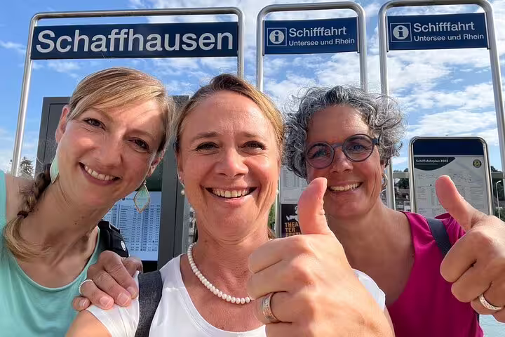 Smiling tourists at Schaffhausen station signs, ready for a self-guided scavenger hunt tour and city sights