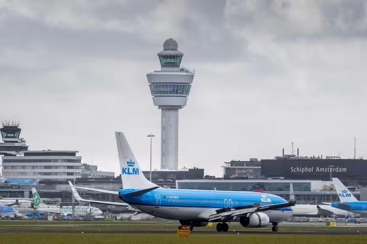 KLM aircraft at Amsterdam Schiphol with control tower, pickup point for private transfer from Schiphol to Antwerp
