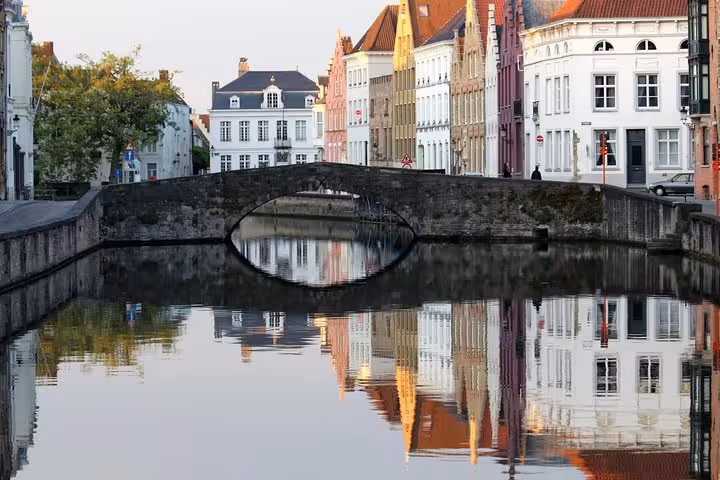 Stone bridge over Bruges canal with colorful facades, seen on Schiphol Airport to Bruges private transfer